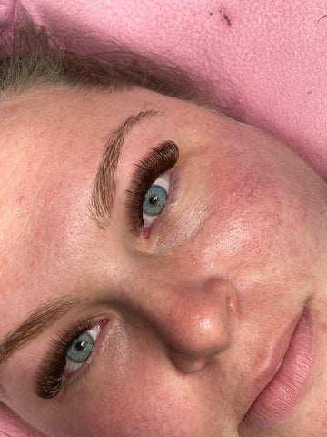 Close-up of woman with premium lash extensions on pink towel, Leo Lash Range