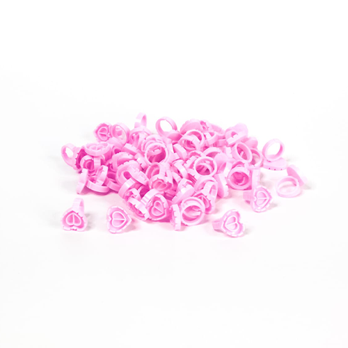 Pink heart-shaped lash glue rings for lash extension application on white background